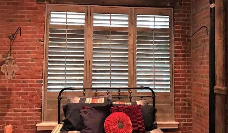 Reclaimed wood shutters surrounded by brick wall.
